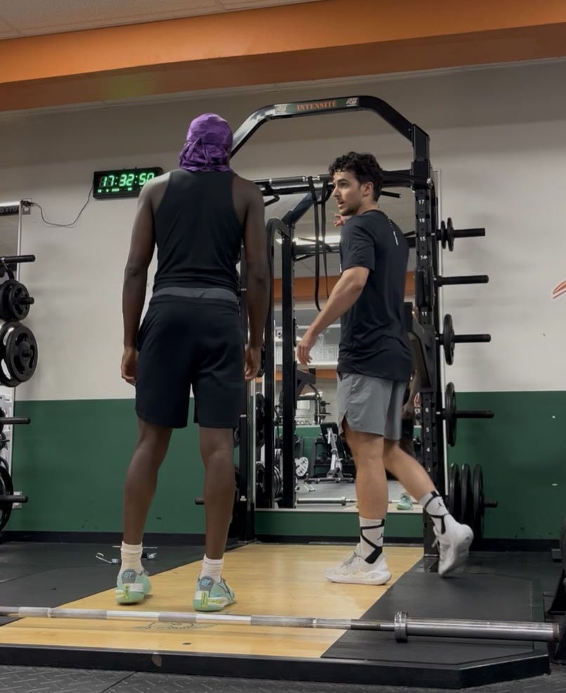 Corentin Hery en train de coacher un athlète en salle de musculation
